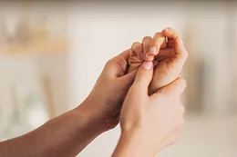 Des mains posées sur la plante d’un pied, les pouces appuyés sur un point.