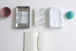 Sur le bureau blanc du cabinet, un bâton de moxa sous emballage, entre le plateau d’aiguilles et deux ventouses en verre.
